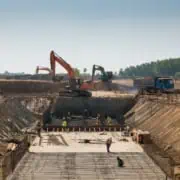 Baustelle mit Bauarbeitern, Baggern und Krandiensten bei Tiefbauarbeiten, Sicherungsmaßnahmen im Einsatz.